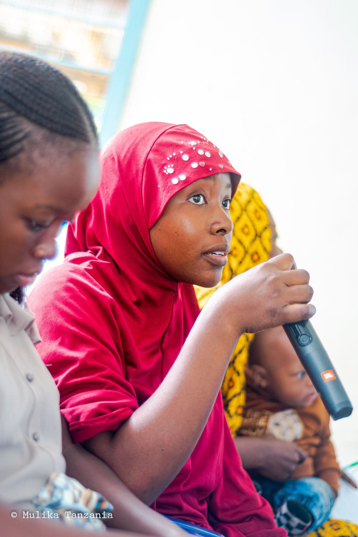 A young member listening closely, microphone in hand