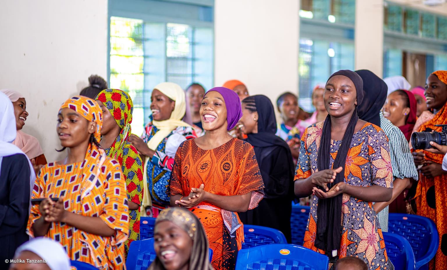 Members laughing and applauding during a community meeting
