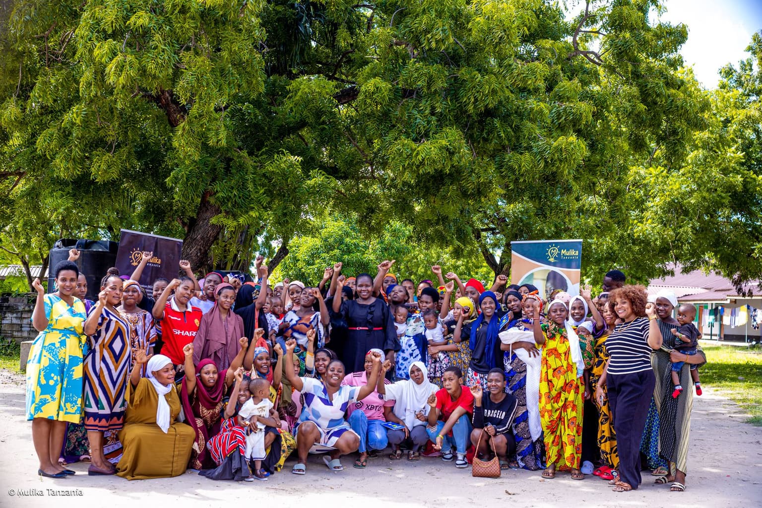A YEE youth cohort celebrating together under the trees in Tanzania